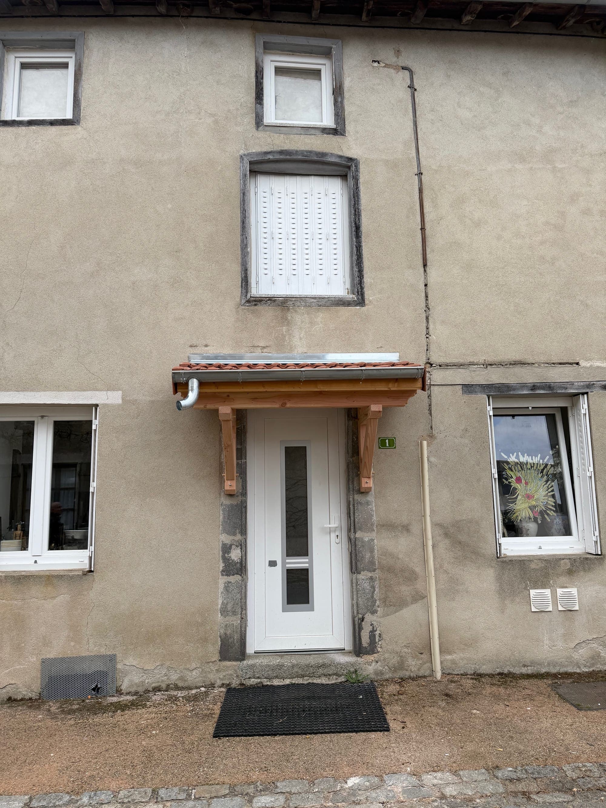 Auvent bois au-dessus d'une porte d'entrée avec gouttière zinc, chantier Belon