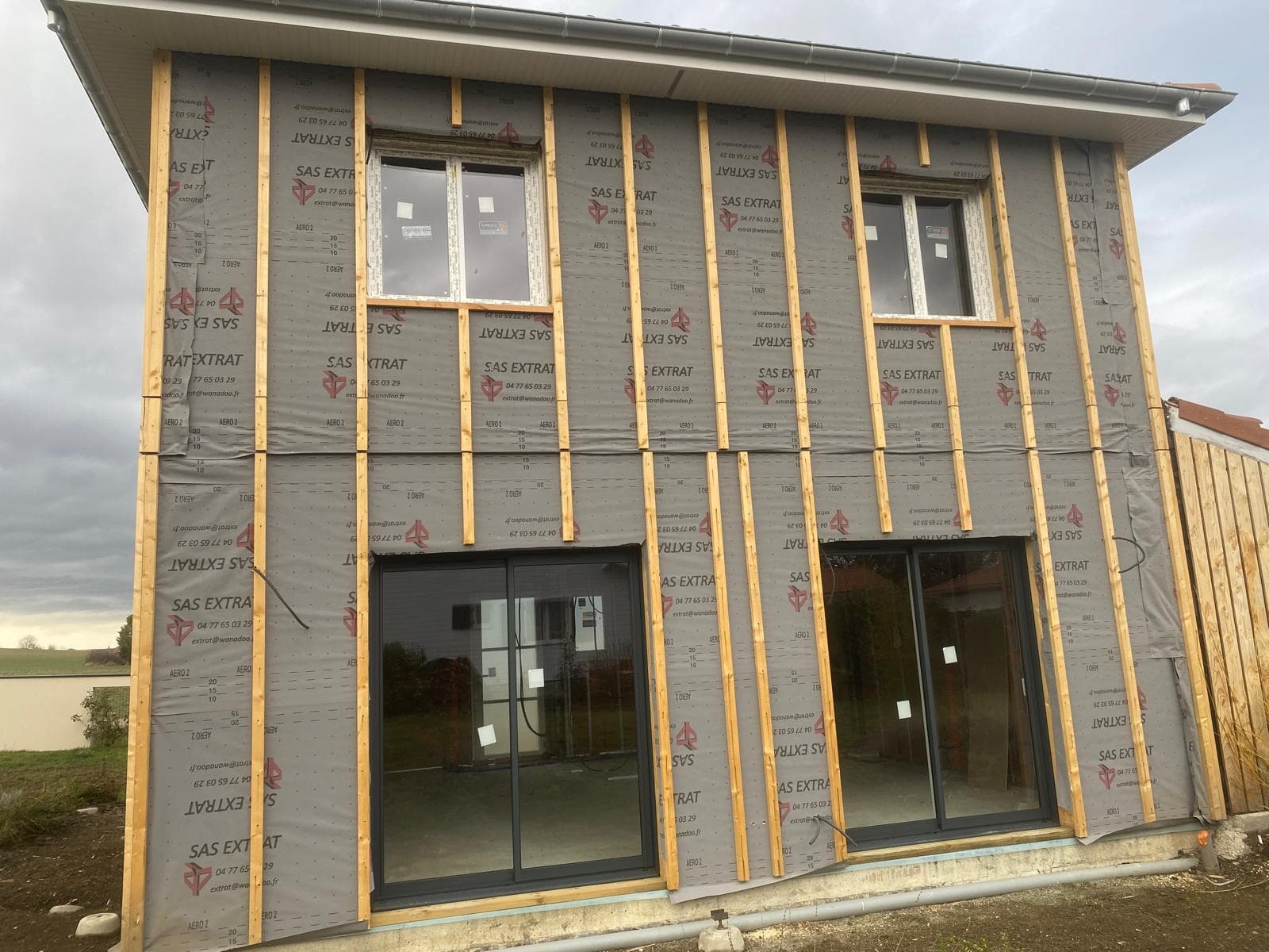 Maison à ossature bois avec pare-pluie et grandes baies vitrées posées