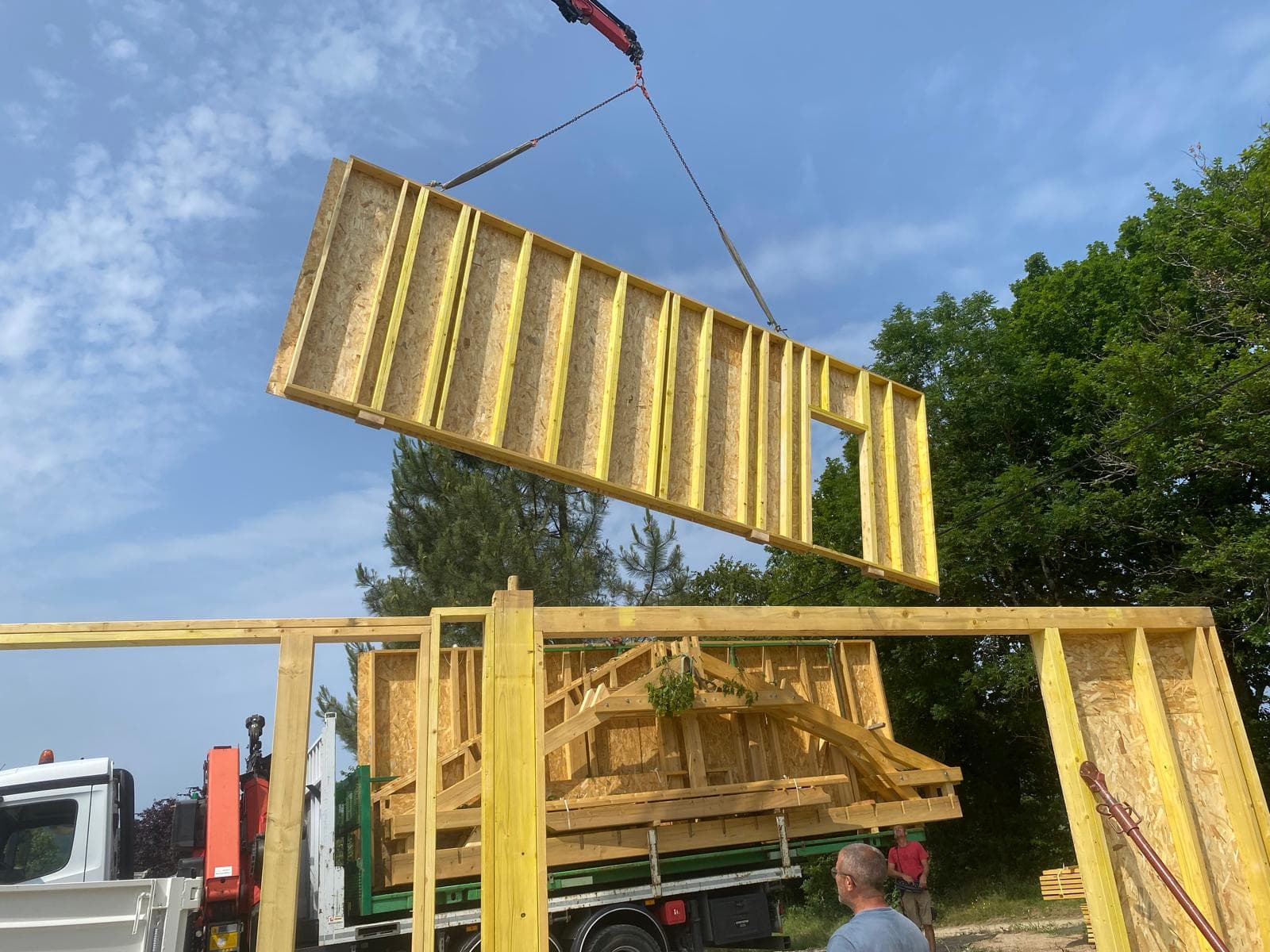 Mur à ossature bois préfabriqué levé à la grue sur un chantier d'extension