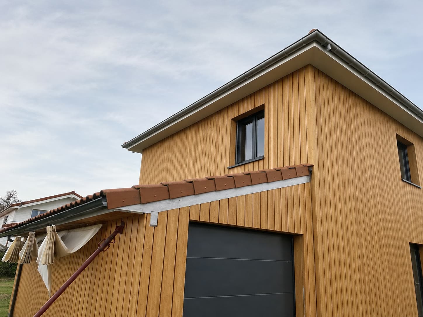 Maison à ossature bois habillée d'un bardage bois vertical, réalisée par Extrat